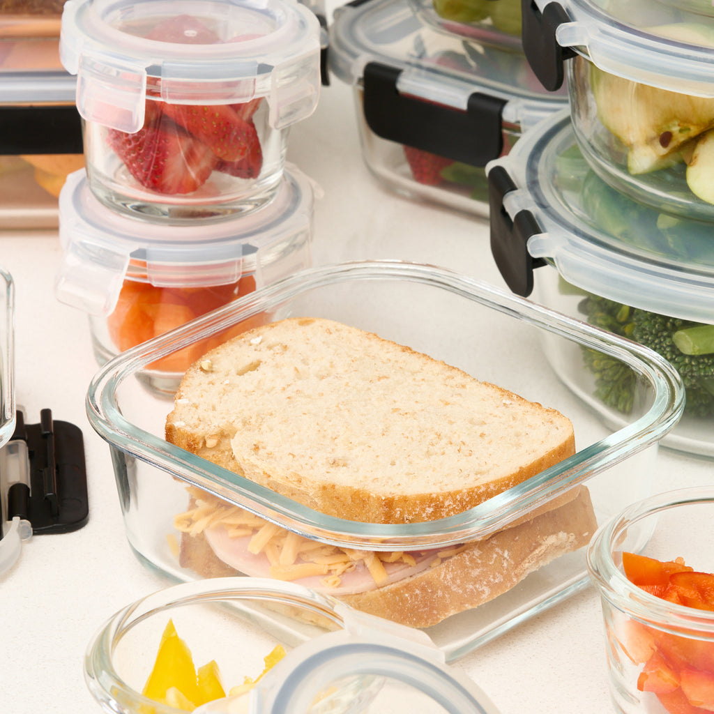 Close-up of an open Storinity glass container holding a sandwich, surrounded by other filled containers