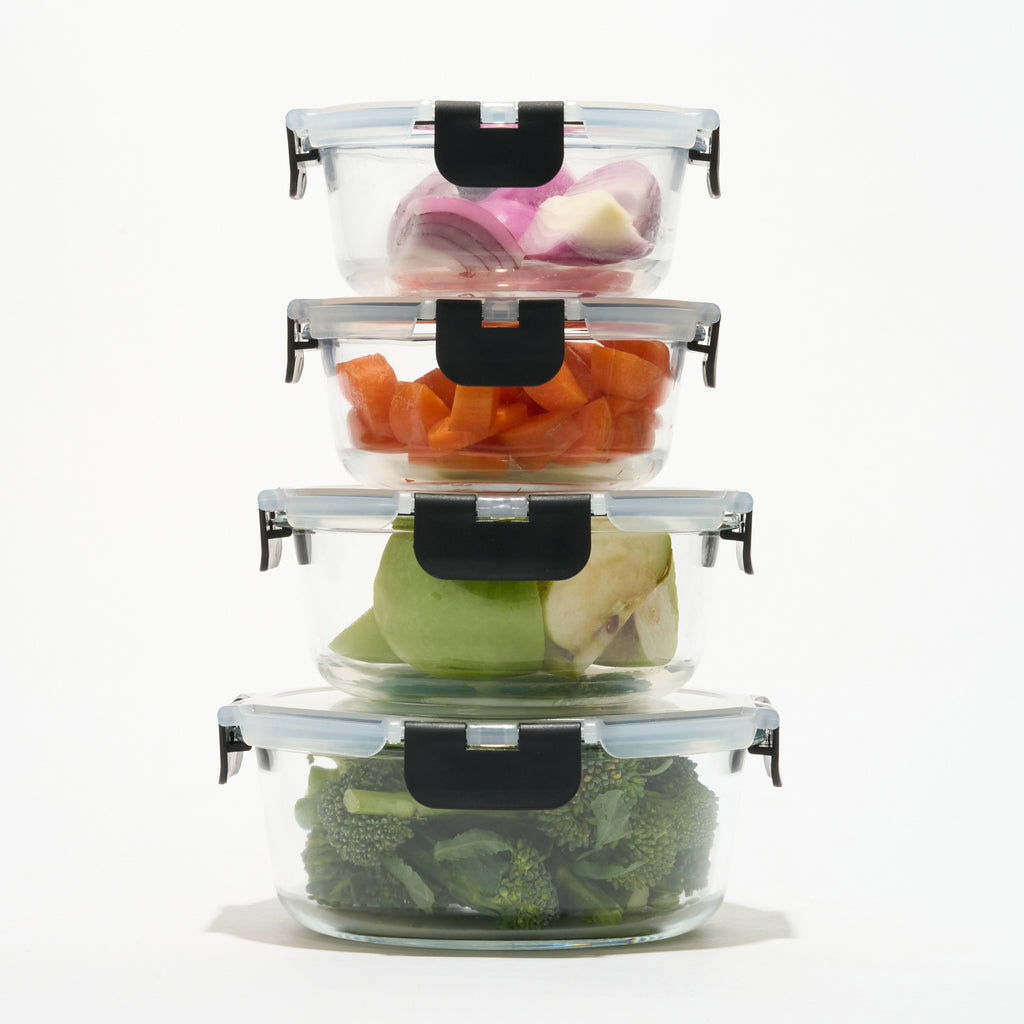 Stack of four round Storinity glass containers filled with onion, carrot, apple and broccoli