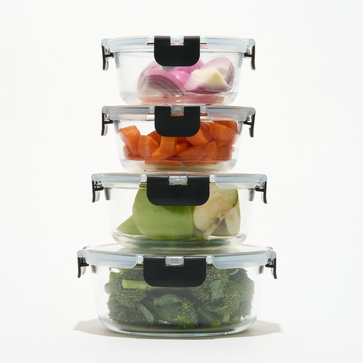 Stack of four round Storinity glass containers filled with onion, carrot, apple and broccoli