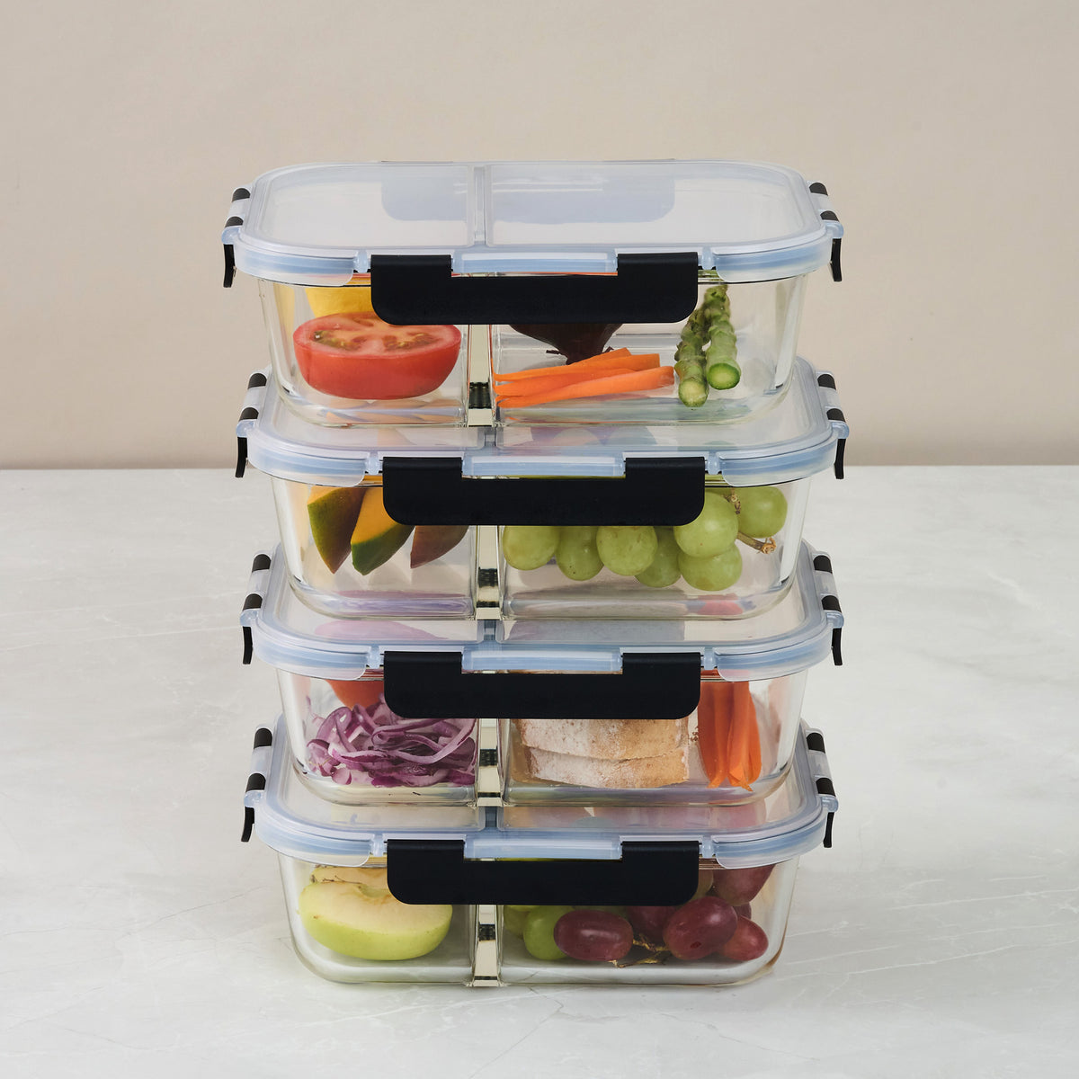 Stack of four Storinity 8-Piece 1500ml Glass Containers, each divided in two and filled with fruit, vegetables and a sandwich