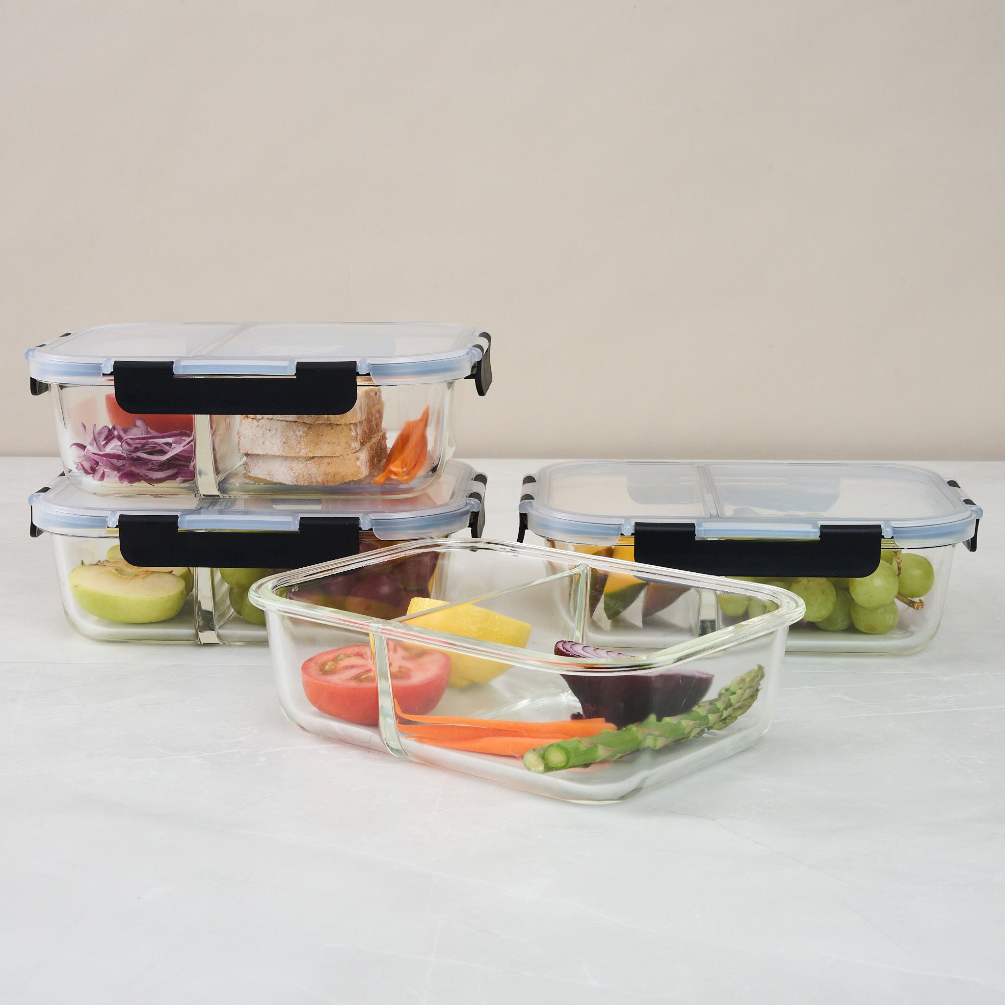 Three Storinity divided glass containers on a counter, one open showing tomato, lemon, beetroot and asparagus