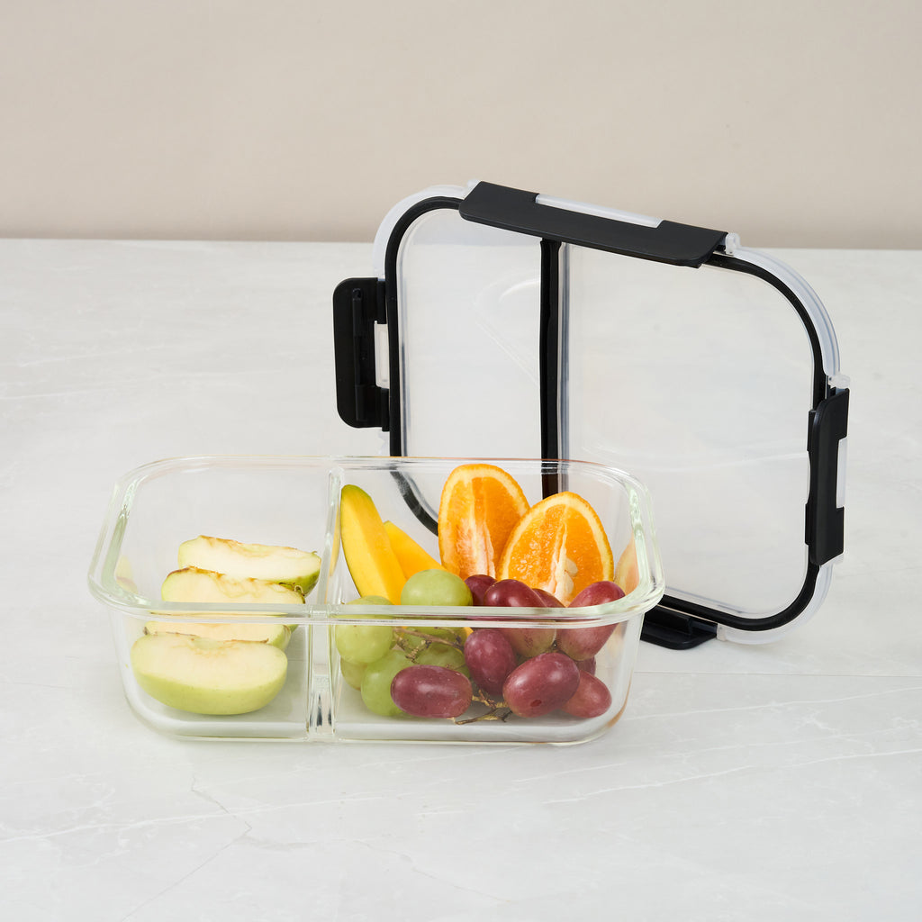 Storinity divided glass container filled with apple, mango and orange, with the lid propped open behind it