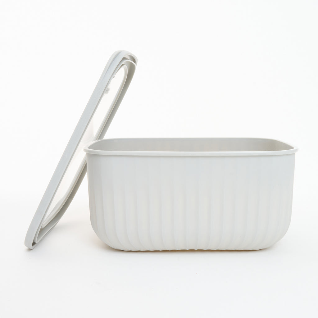 Empty white Storinity rectangular nesting bowl with the lid propped up beside it