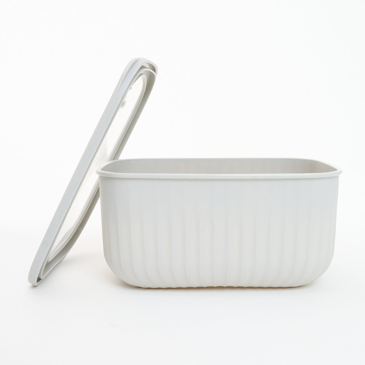 Empty white Storinity rectangular nesting bowl with the lid propped up beside it