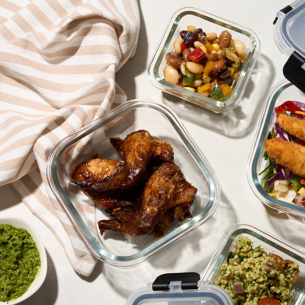 Close-up of Storinity glass containers filled with bean salad, glazed chicken wings, crumbed fish and pesto rice salad