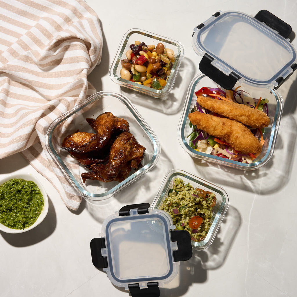 Overhead view of Storinity glass containers filled with bean salad, chicken wings, crumbed fish and pesto rice salad