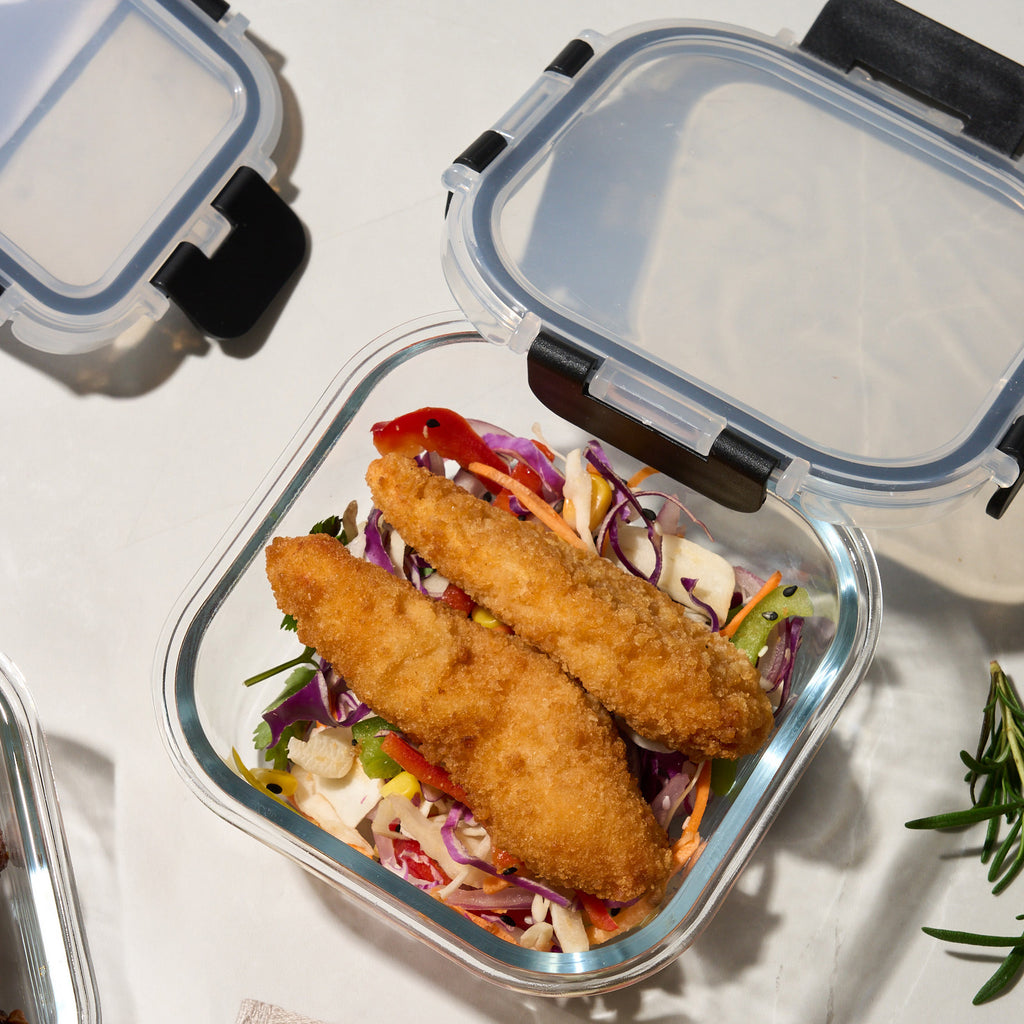 Close-up of an open Storinity glass container filled with crumbed fish sticks over red cabbage slaw