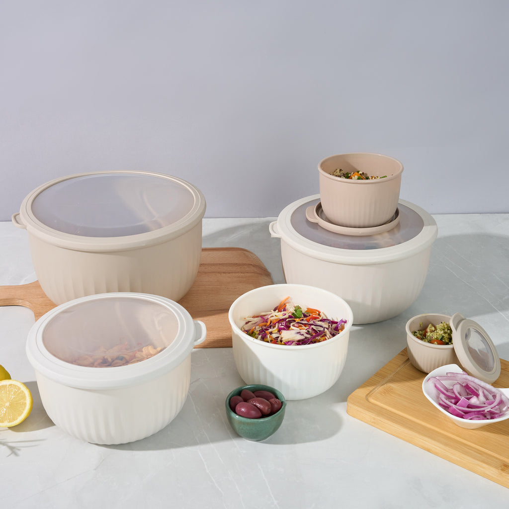 Storinity nesting bowls filled with pasta salad and quinoa salad, with olives, coleslaw, lemon and red onion on a counter
