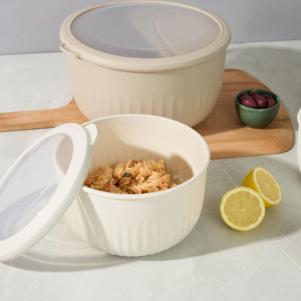 Open Storinity nesting bowl of pasta salad beside a closed lidded bowl, olives and lemon halves