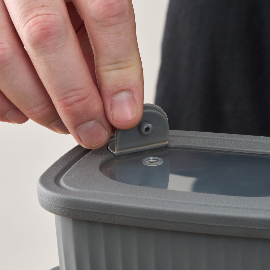 Close-up of a hand pressing the vent button on a Storinity rectangular bowl's lid