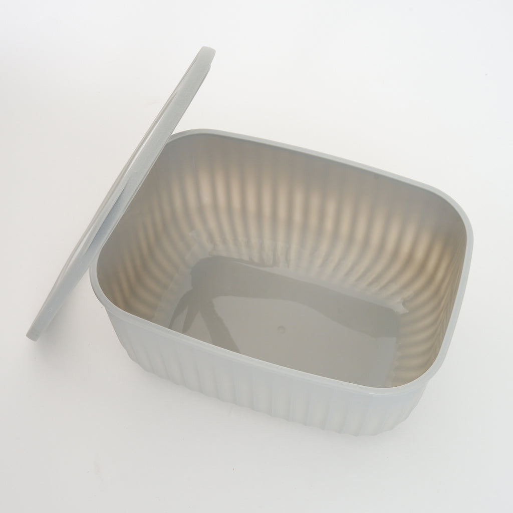 Empty grey Storinity rectangular bowl with the lid propped up beside it, showing the ribbed interior