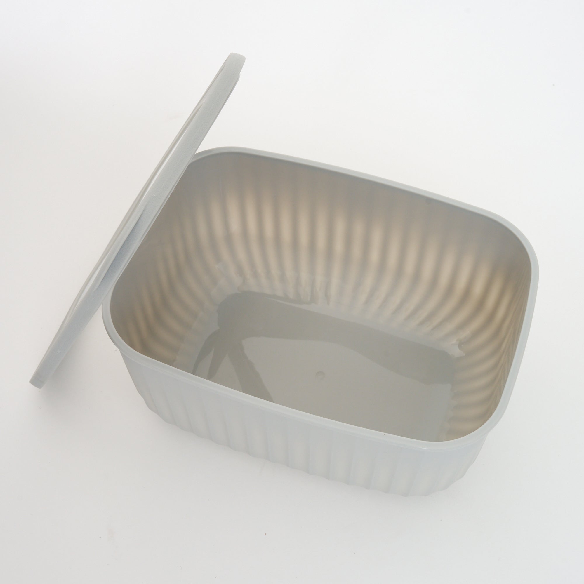 Empty grey Storinity rectangular bowl with the lid propped up beside it, showing the ribbed interior